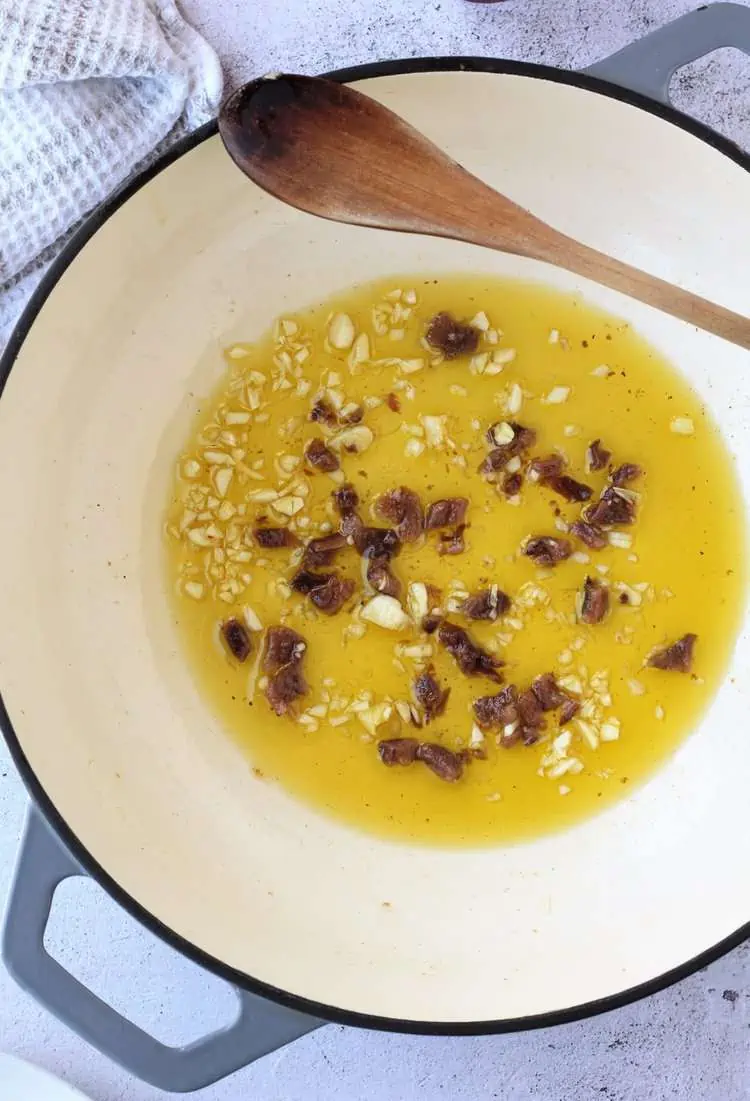 Garlic and anchovies in oil in large pan.