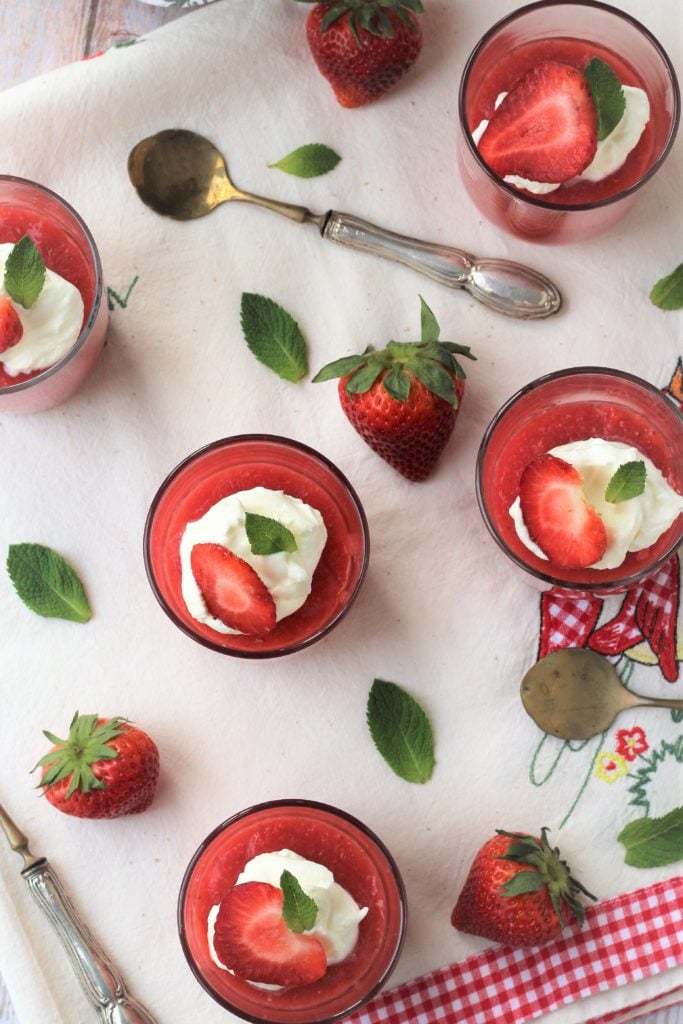 Overhead view of glasses with strawbery pudding with whipped cream and mint leaves.