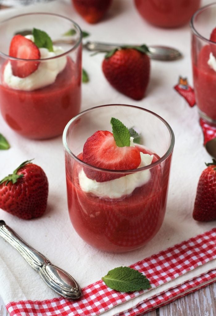 Glass with strawberry pudding topped with whipped cream and mint.