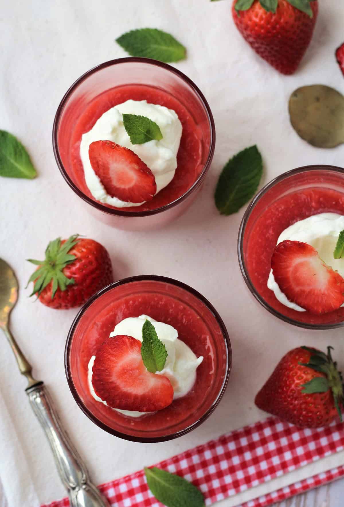Glasses filled with Sicilian gelo di fragole topped with whipped cream, strawberry half and mint leaf.