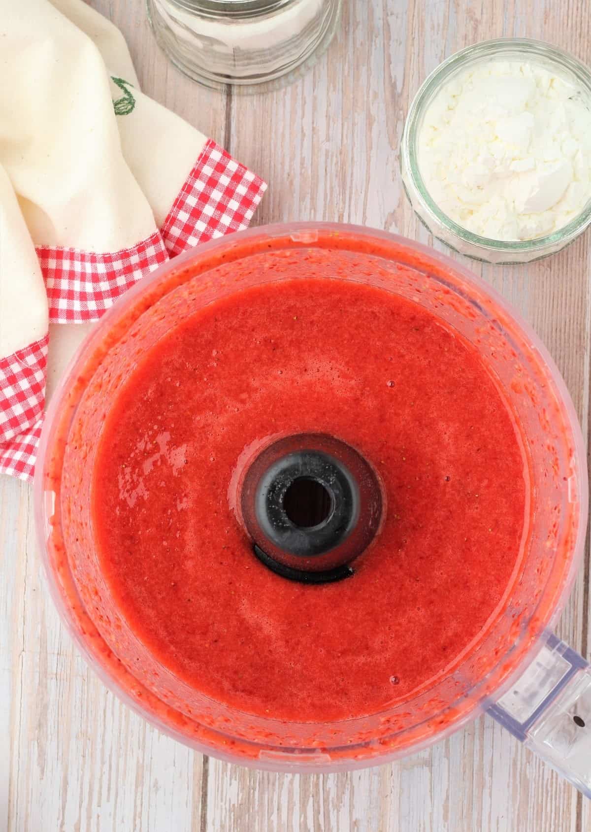 Pureed strawberries in food processor bowl with sugar.