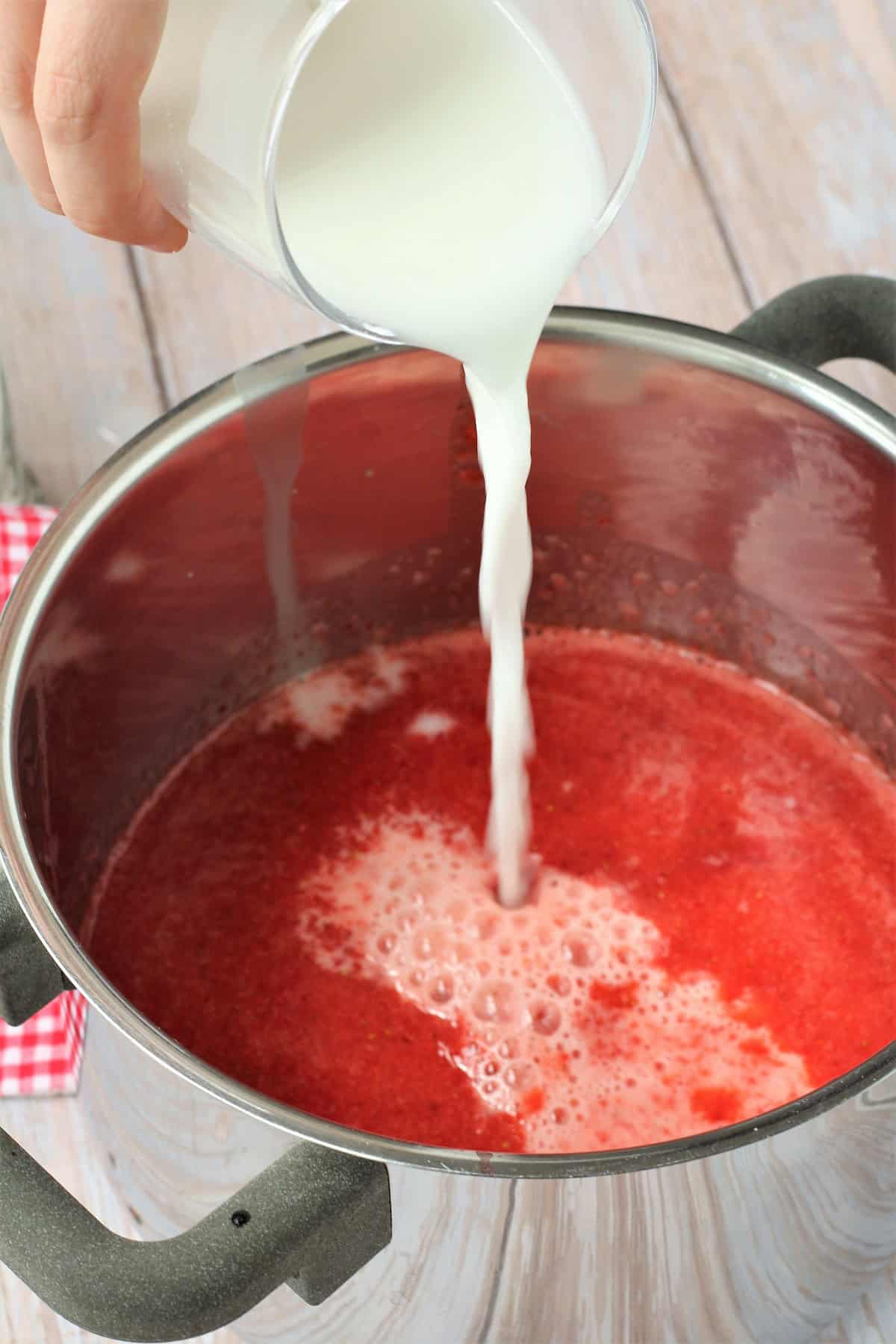 Pureed strawberry mixture in sauce pan with cornstarch slurry poured into it. 