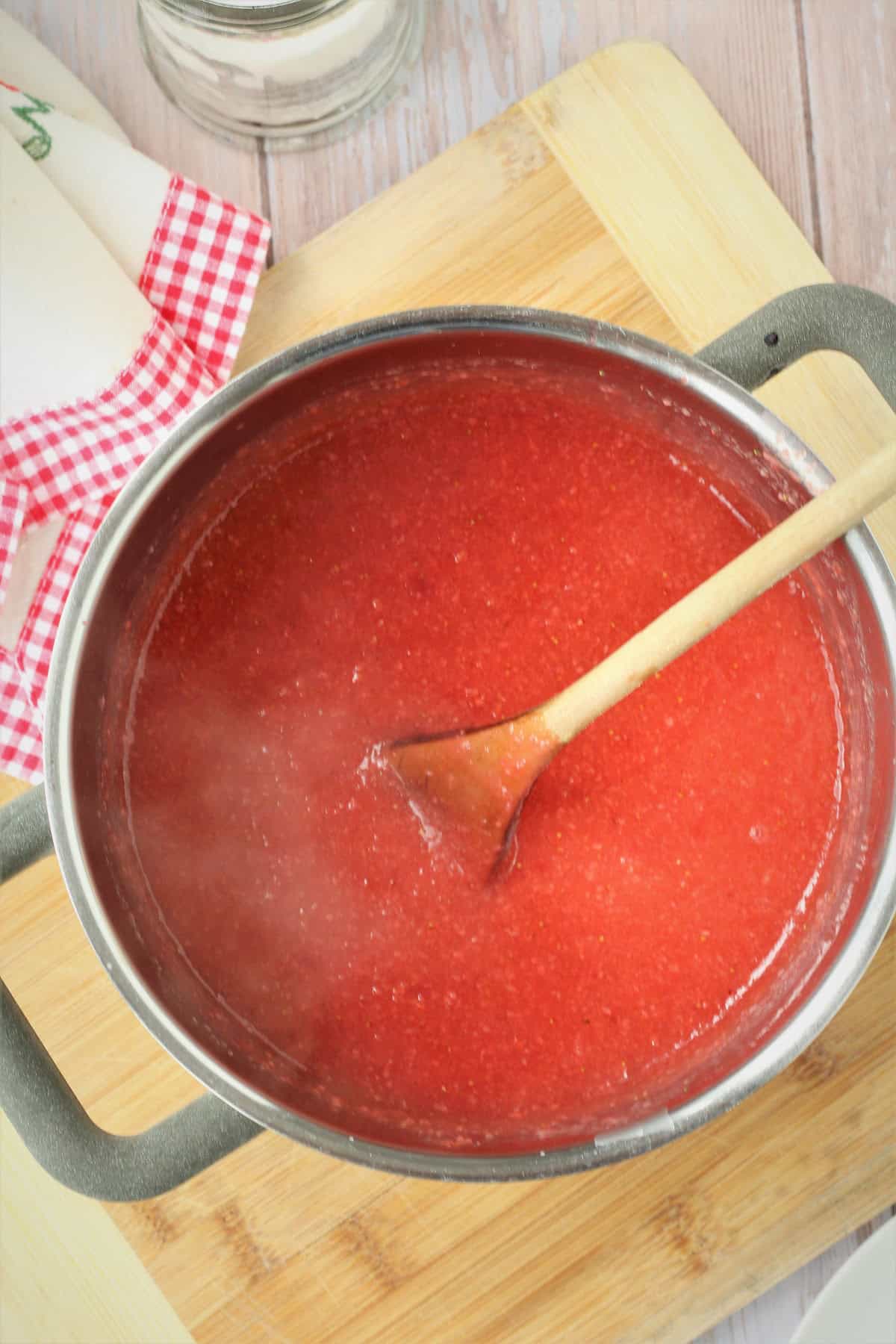 Sicilian strawberry pudding mixture in sauce pan with wooden spoon.