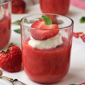 Sicilian strawberry pudding (gelo di fragole) in glasses topped with whipped cream strawberry half and mint leaf.
