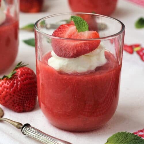 Sicilian gelo di fragole in glasses with whipped cream, strawberry half and mint leaf.