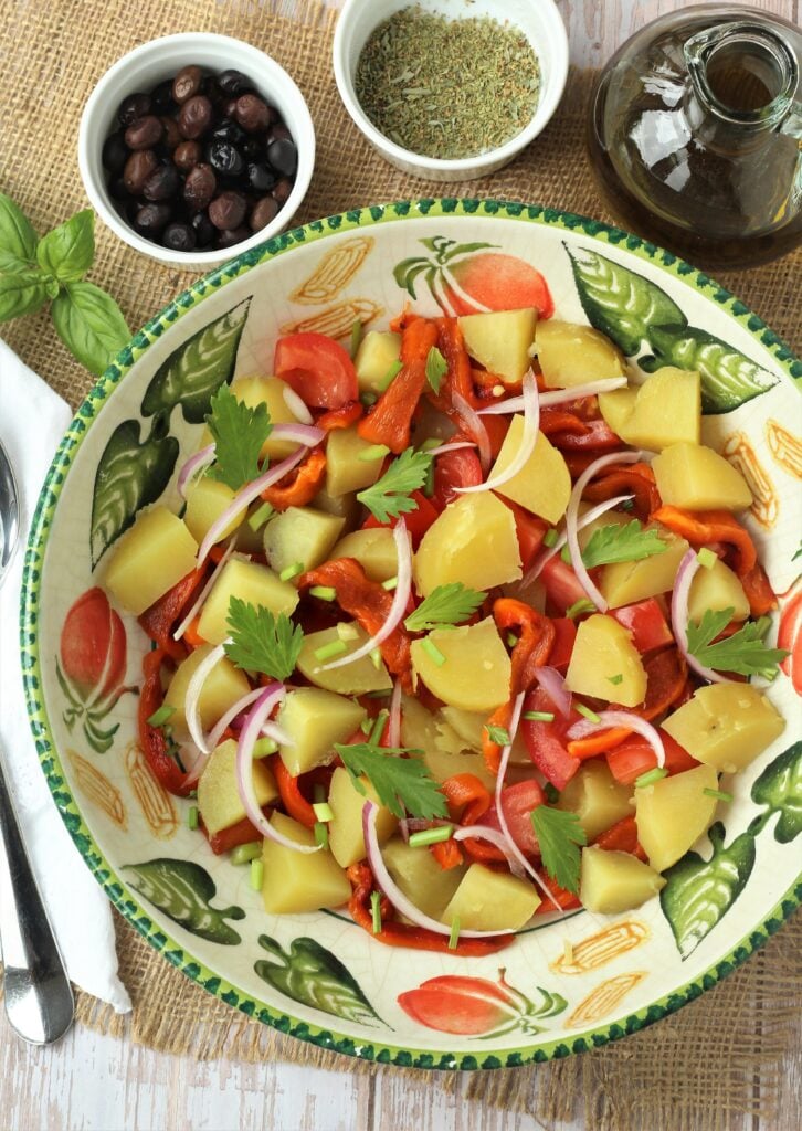 Potatoes, red peppers, tomatoes, red onion and celery in salad bowl.