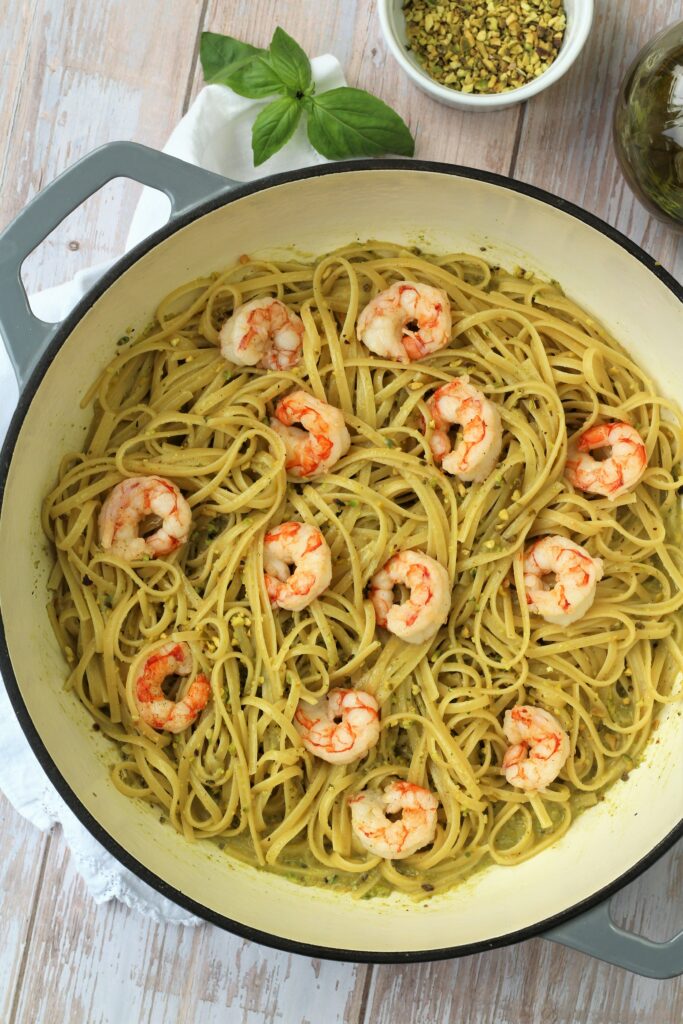 Large skillet filled with pistachio pesto pasta with shrimp.