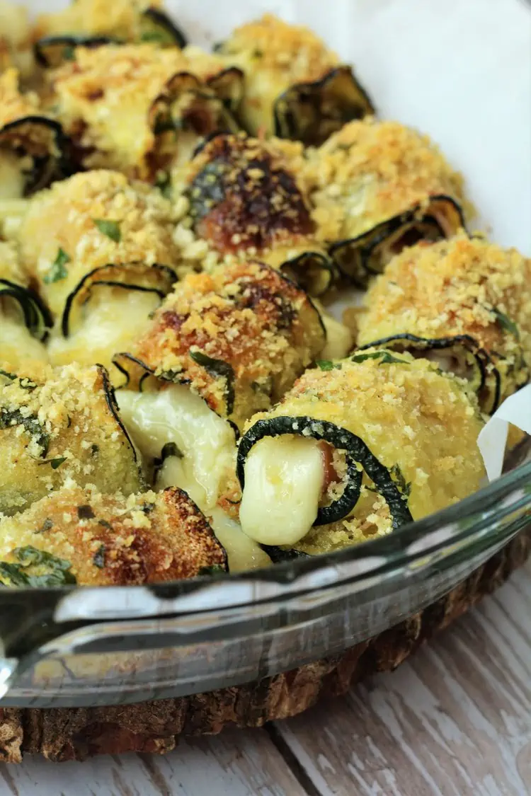Prosciutto and cheese zucchini roll ups in round baking dish.