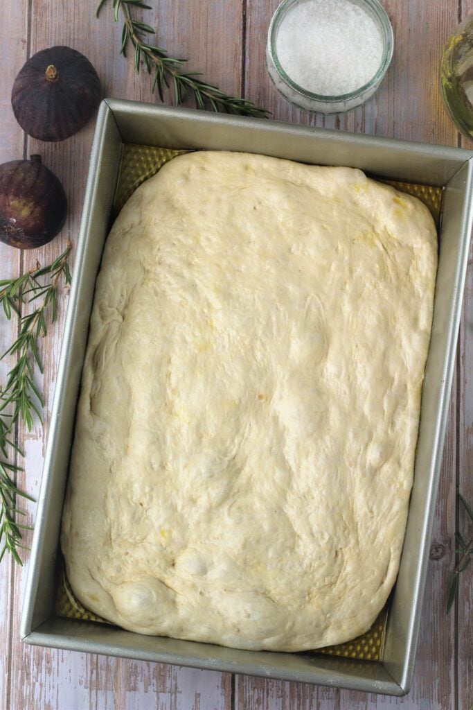 Focaccia dough spread in baking pan.