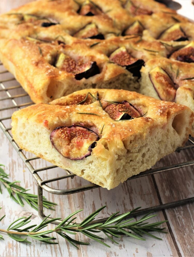 Wedge of fig rosemary focaccia on cooling rack.
