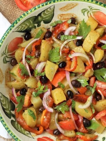 Italian potato salad with roasted red peppers and tomatoes in large bowl.