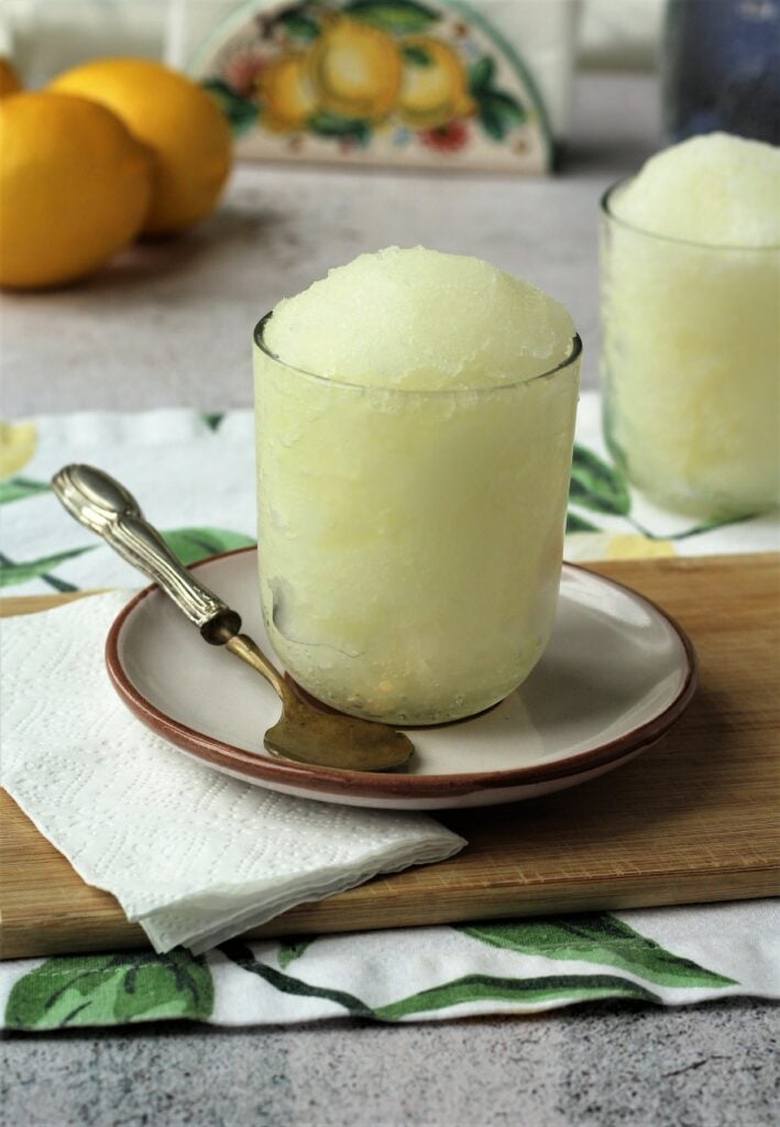 Granita al limone in glasses with spoon and lemons.