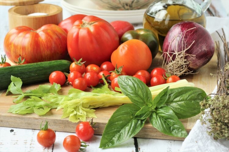 Tomatoes, cucumber, celery, basil and red onion on wood board