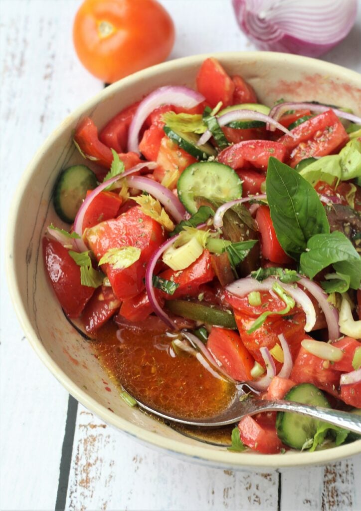 Bowl of tomato cucumber salad with spoon.