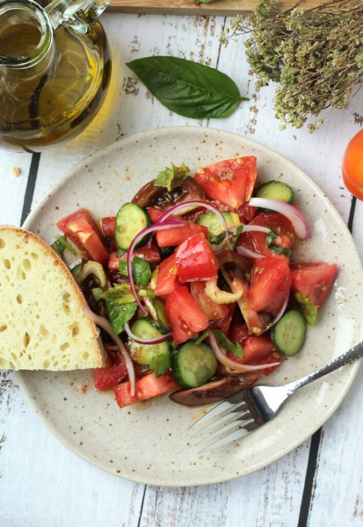Plated tomato cucumber onion salad with bread.