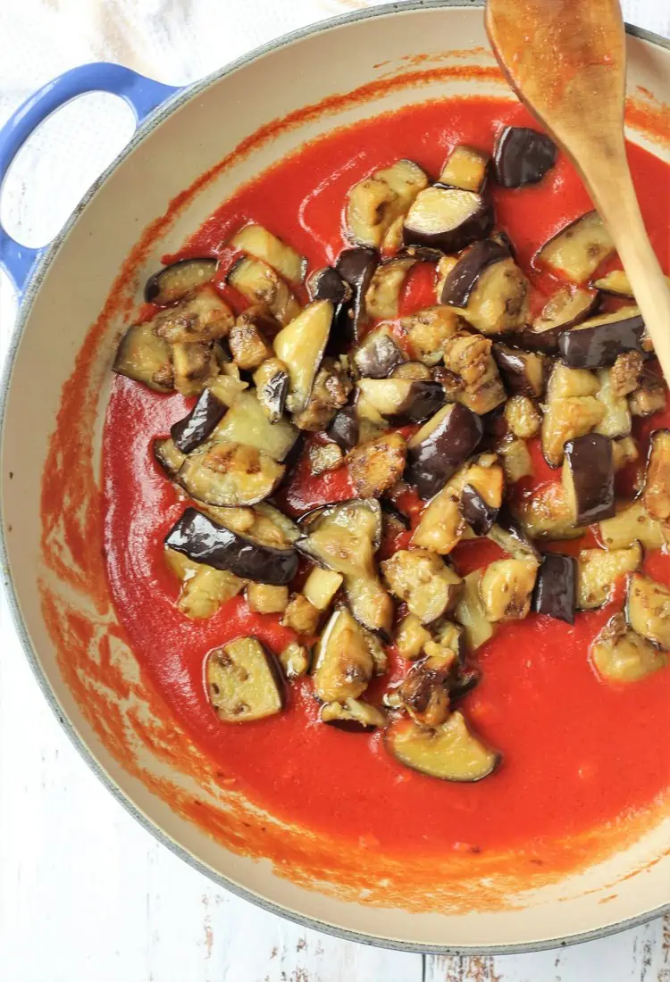 Eggplant cubes added to tomato sauce in skillet.