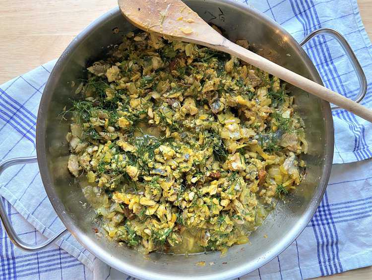 Sardine sauce with wild fennel, pine nuts, raisins and saffron in skillet.