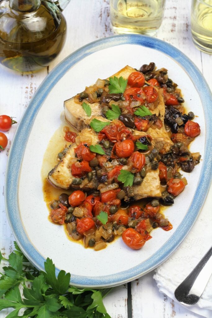 Plated sicilian swordfish with tomatoes, capers and olives.