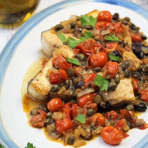 Plated sicilian swordfish with cherry tomatoes.