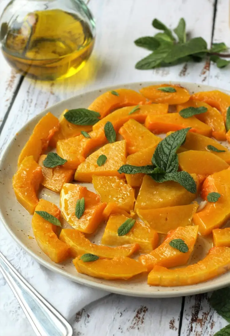 Sweet and sour squash topped with mint on plate.