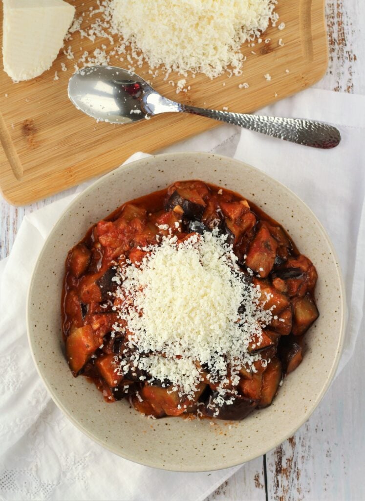 Eggplant sauce in bowl topped with grated ricotta salata.