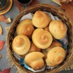 Basket filled with biscotti di San Martino surrounded by wine glass, grapes and leaves.