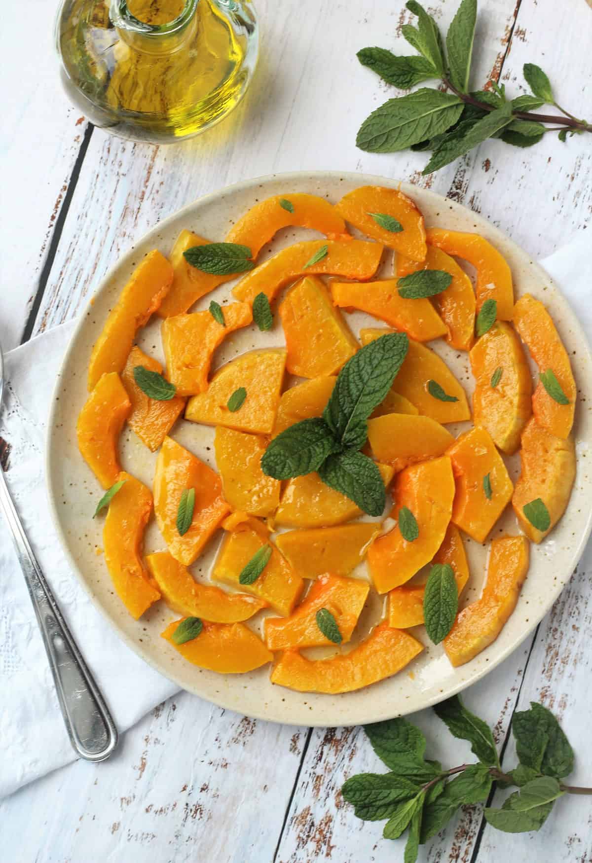 Sicilian sweet and sour squash slices topped with mint leaves on plate.