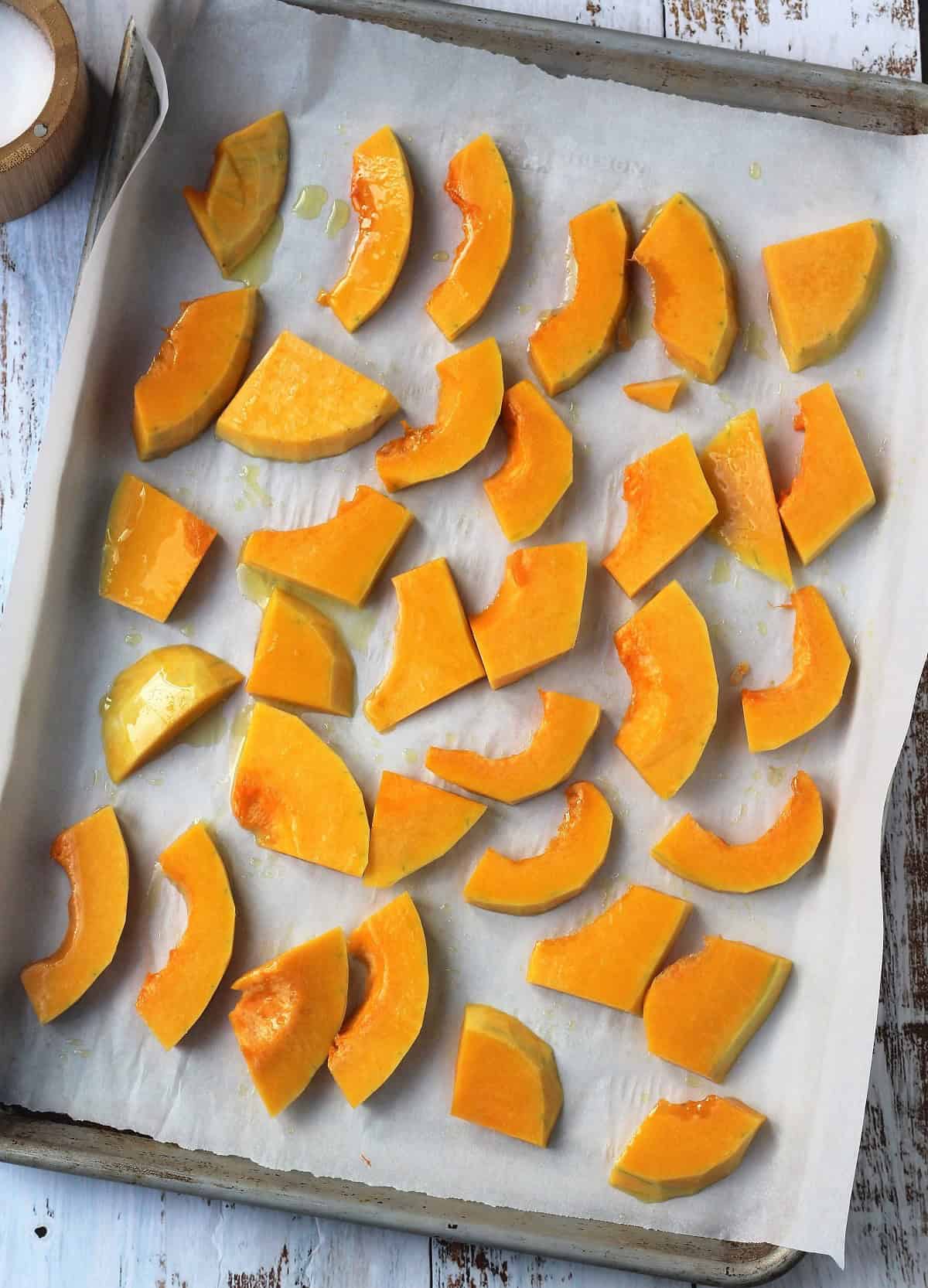 Sliced squash on baking sheet for roasting.
