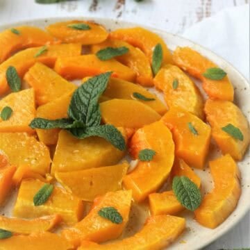 Sweet and sour squash slices topped with mint leaves on plate.