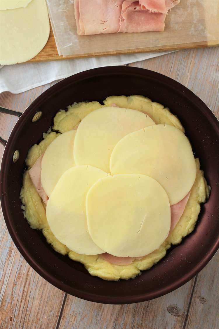 Skillet potato cake topped with ham and cheese.