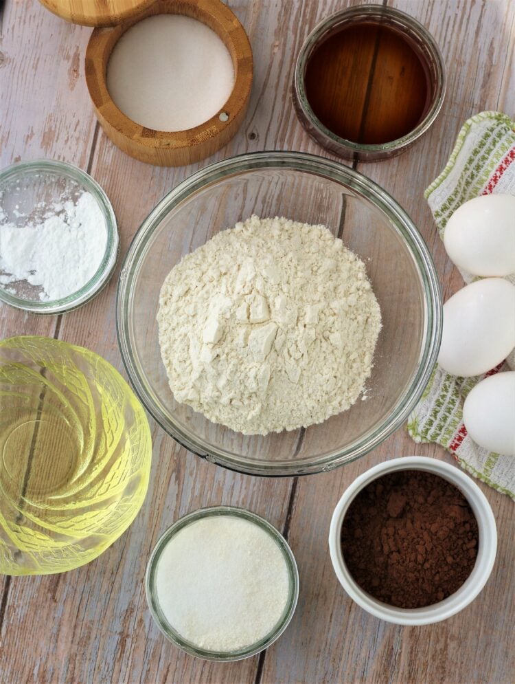 Bowls of flour, sugar, cocoa powder, oil, vanilla, salt and eggs.