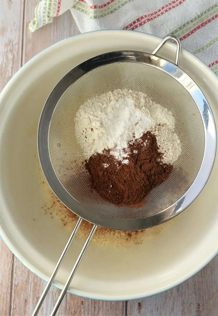 Flour and cocoa sifted over mixing bowl.