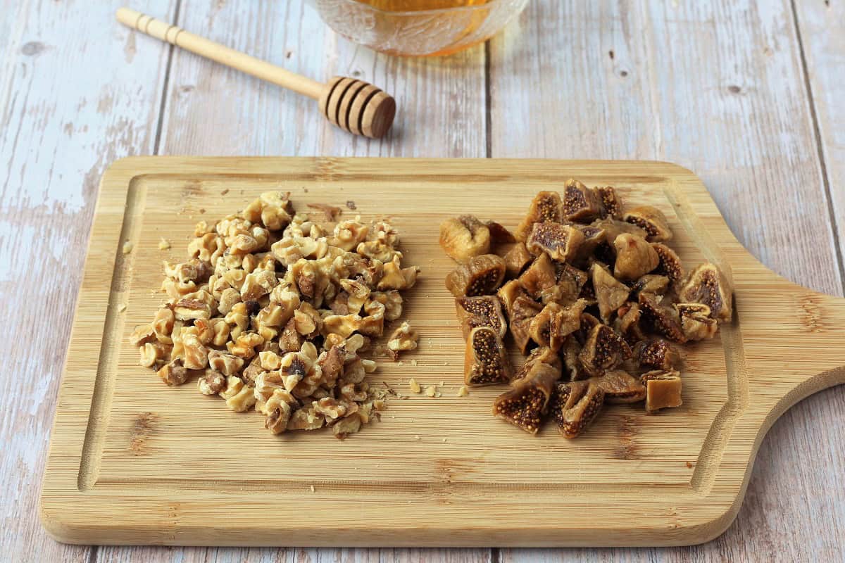 Soaked figs chopped on wood board along with chopped walnuts.