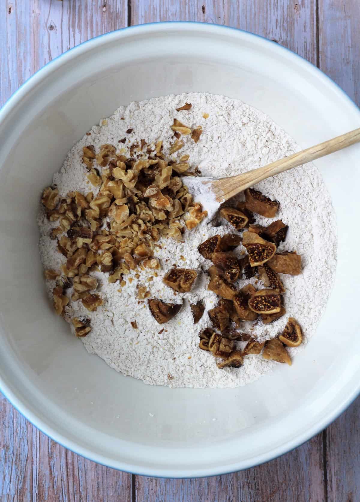 Chopped figs and walnuts added to bowl with dry ingredients for fig walnut bread.
