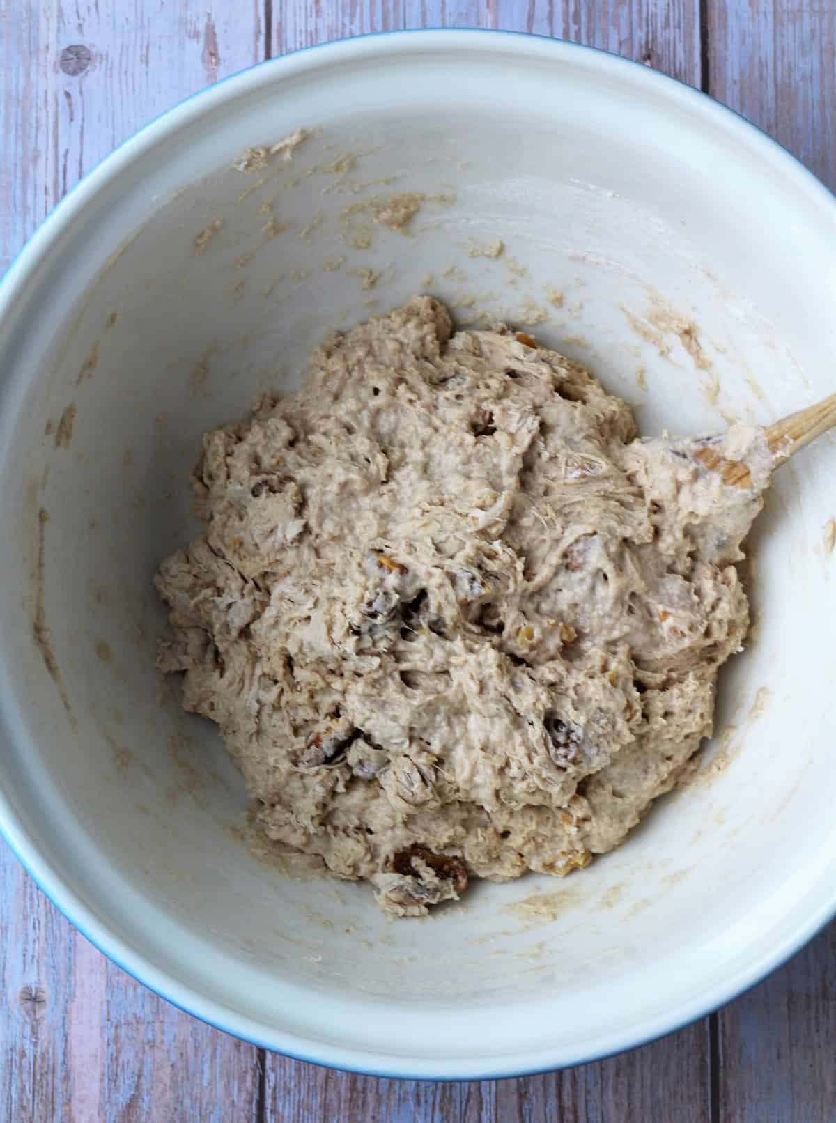 Shaggy no knead fig and walnut bread dough in bowl with wooden spoon.