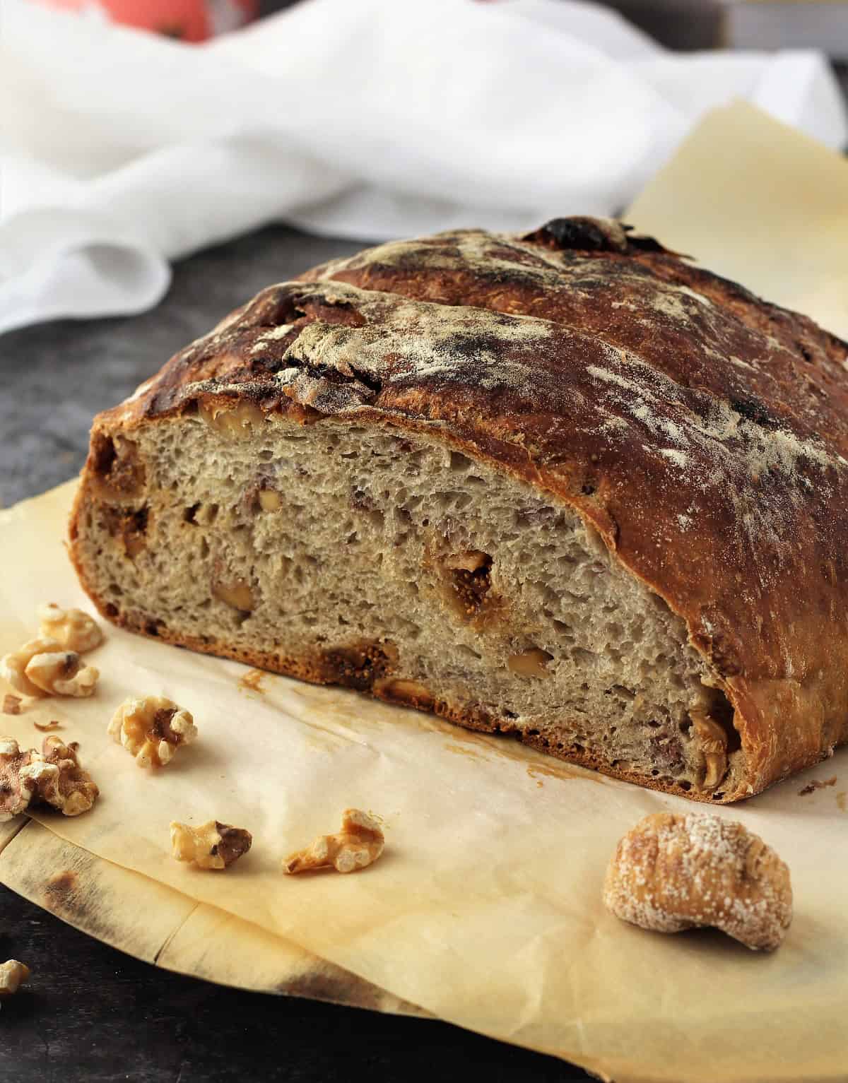 No knead fig and walnut bread cut open on wood board.