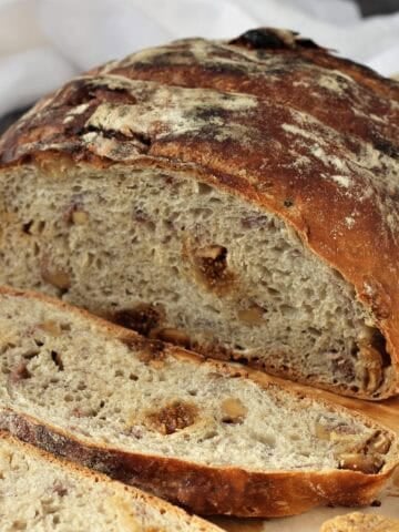 No knead fig walnut bread cut open on wood board.