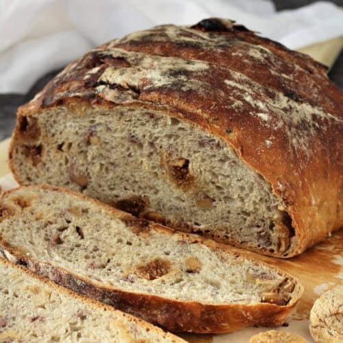 No knead fig walnut bread cut open on wood board.