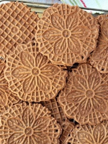 Chocolate pizzelle laid out on wire rack.