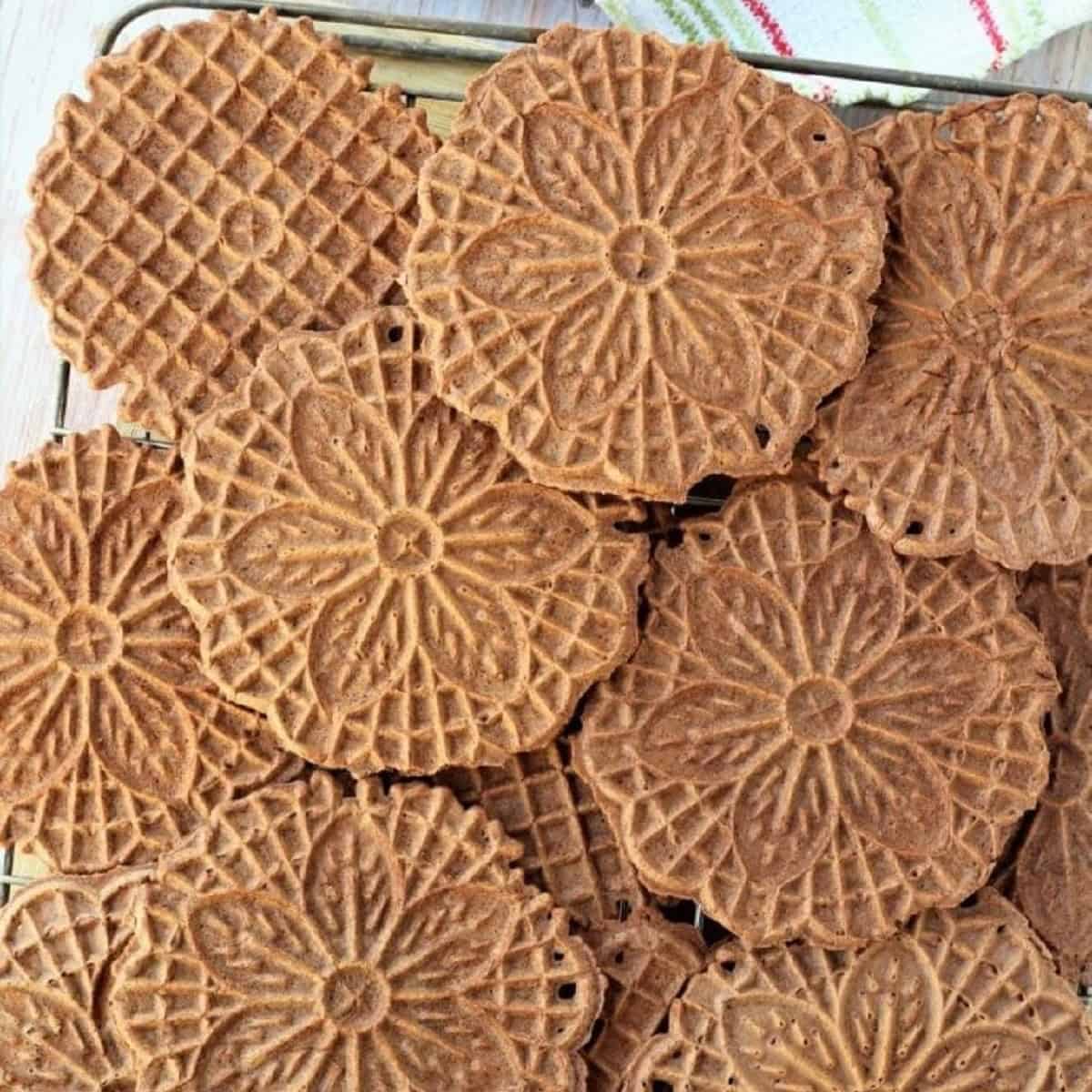 Chocolate pizzelle laid out on wire rack.