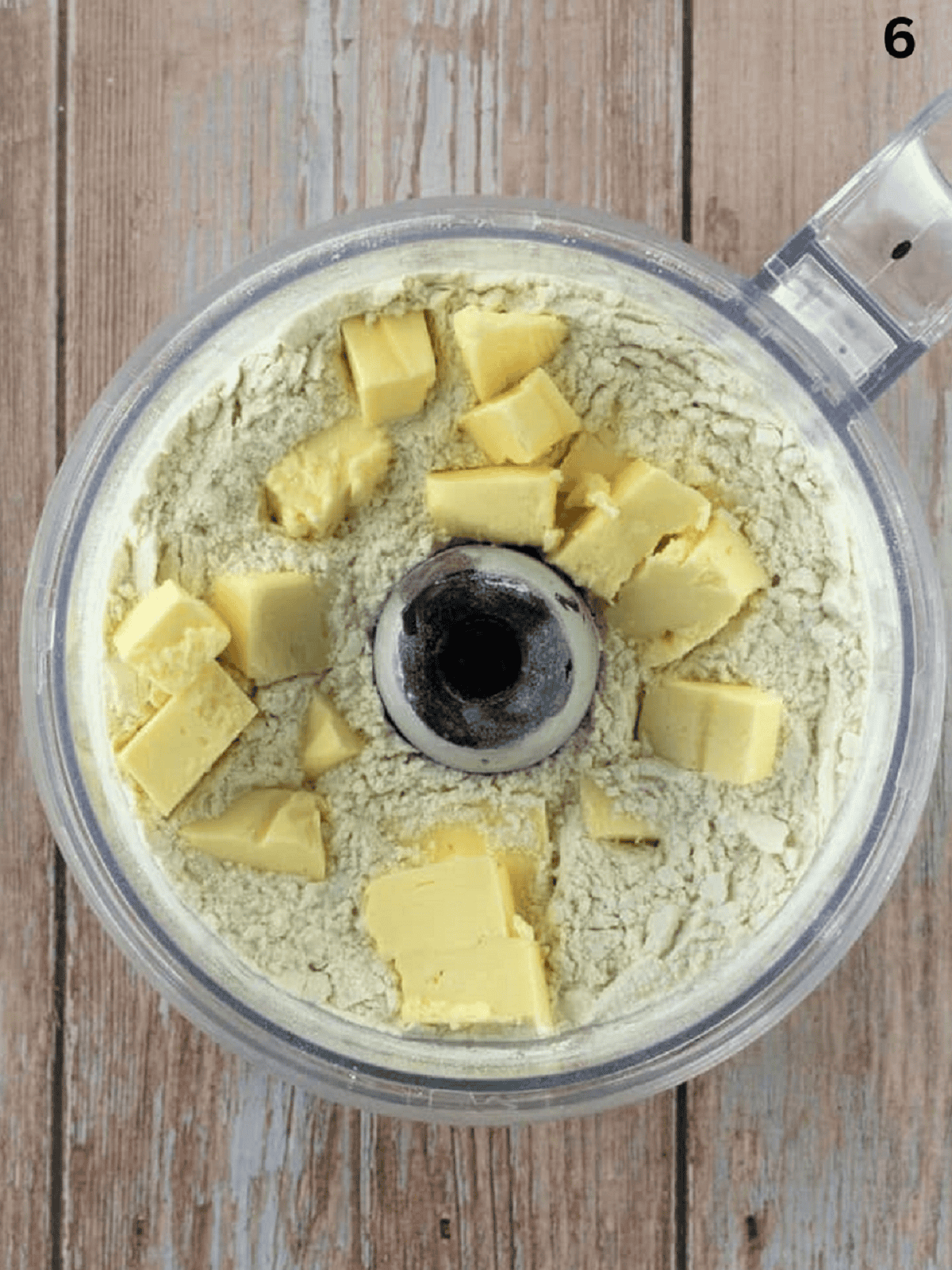 Cubed butter added to food processor bowl with dry ingredients for cuccidati dough.