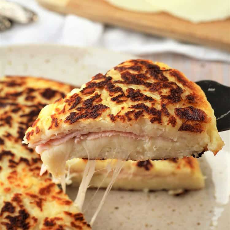 Wedge of pan fried potato focaccia with ham and cheese.
