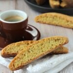Anise biscotti next to coffee cup on napkin.