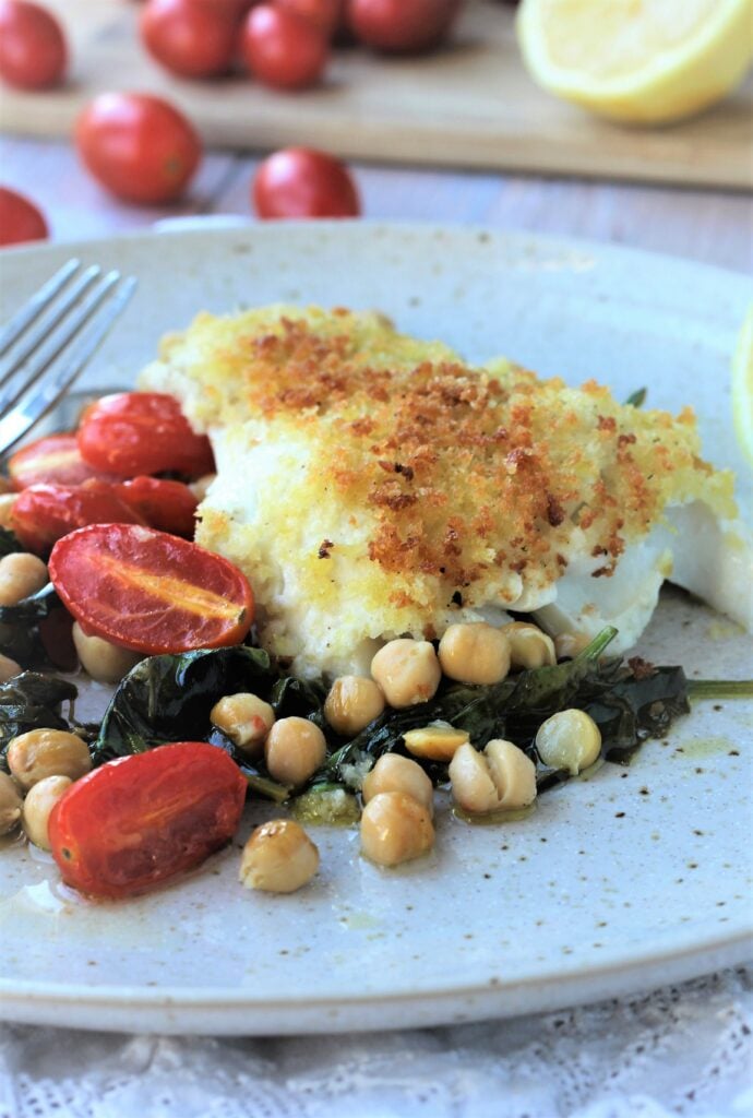 Oven baked fish with breadcrumbs over chickpeas, spinach and tomatoes.