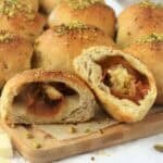 Mortadella, pistachio and mozzarella stuffed roll cut open on wood board.