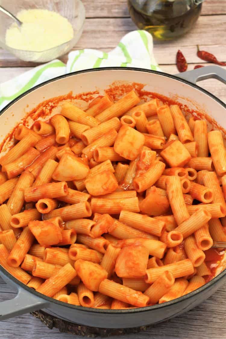 Pasta with potatoes in tomato sauce in skillet.