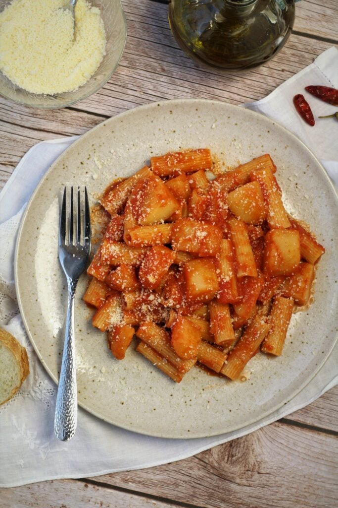 Pasta with potatoes in tomato sauce on plate with fork.