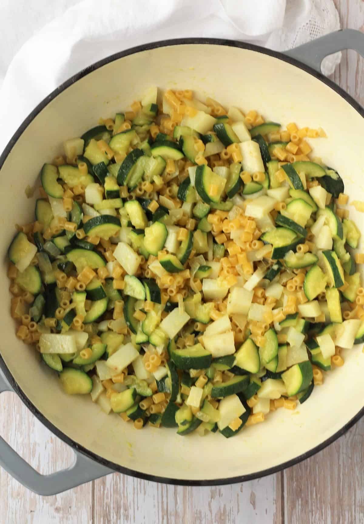 Pasta added to skillet with zucchini and potatoes for risotto pasta.