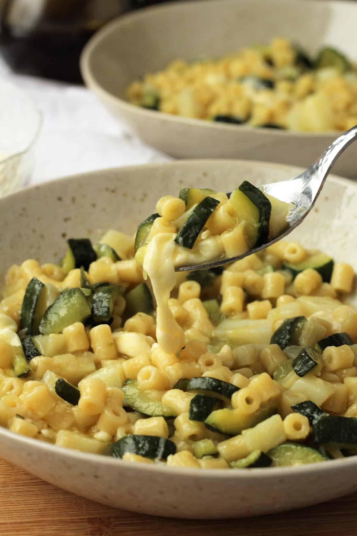 Creamy risotto pasta with zucchini spooned in bowl.