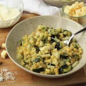 Creamy risotto pasta with zucchini spooned from bowl.